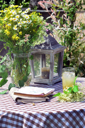Elderberry Lemonade on a Table with Bouquet of Wild Flowers and Wooden Lanternの写真素材