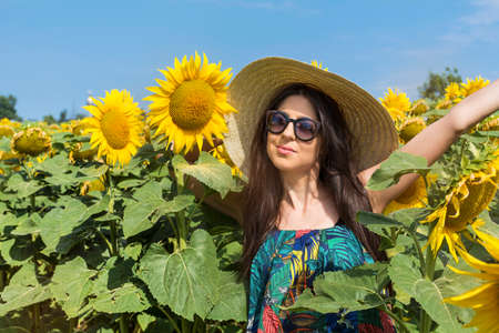 beautiful happy woman with hat smiling in a sunflower fieldの写真素材