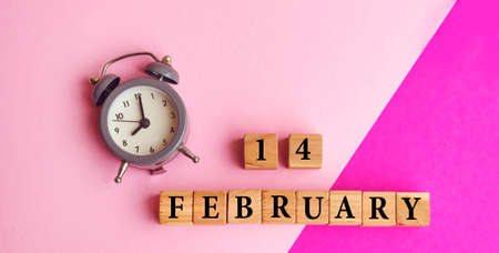 Pink Greeting Card with Wooden Calendar and alarm clock . Wooden cubes with 14 February textの写真素材