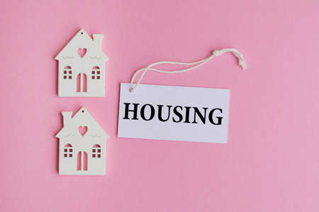 Housing word and wooden mini houses on pink backgroundの写真素材