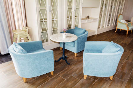 Two blue armchairs and a round coffee table in a spacious roomの写真素材