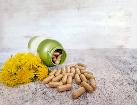 Herbal medicine pills and yellow dandelion flowers on concrete backgroundの写真素材