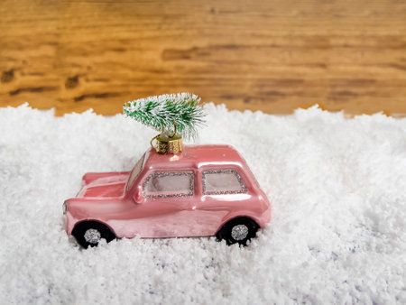 Toy car with christmas tree on the snow in front of wooden backgroundの写真素材