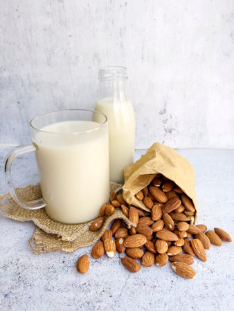 Almond milk in a glass bottle with almonds on a light backgroundの写真素材