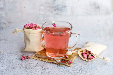 Cup of tea with rose buds on a light concrete background.の写真素材