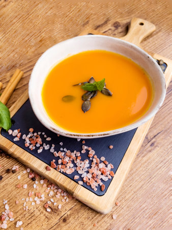 Pumpkin soup with cream and pumpkin seeds on a wooden backgroundの写真素材
