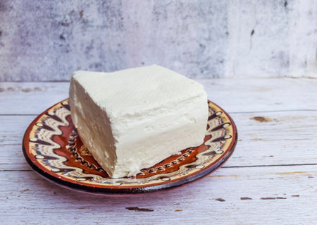 Traditional Greek cheese feta on a plate on a white wooden backgroundの写真素材