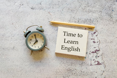 Time to learn concept. Alarm clock and wooden pencil on concrete background.の写真素材