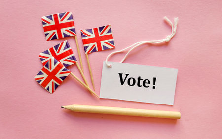 Vote word on paper tag, pencil and United Kingdom flag on pink backgroundの写真素材