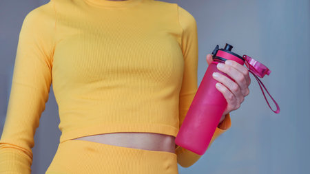 Close up of sportswoman holding bottle of water. Woman in yellow sportswearの写真素材