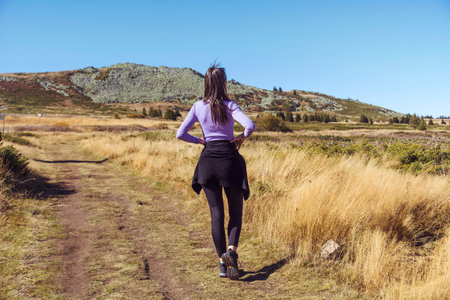 Young woman jogging on a trail in the mountains. Back viewの写真素材