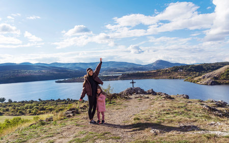 Mother and daughter standing on top of a mountain and enjoying the view
