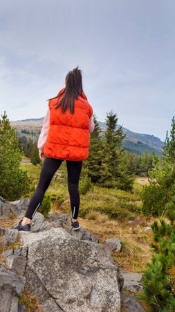 Back view of young woman hiker standing on top of a mountainの写真素材