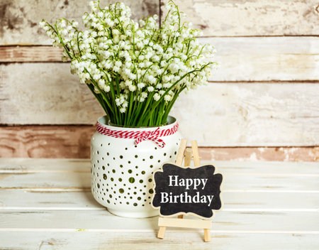 Bouquet of lilies of the valley in a vase and a sign with the inscription Happy Birthdayの写真素材