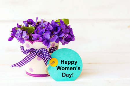 Happy Womens Day card with violets in vase on white wooden backgroundの写真素材