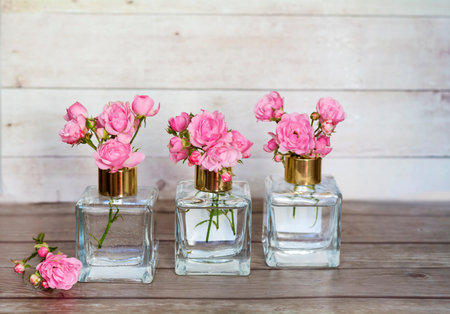 Bottles of perfume with pink roses on wooden background. Vintage styleの写真素材