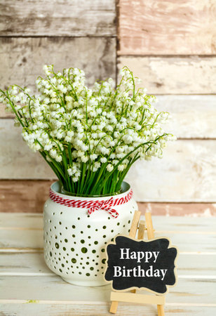 Bouquet of lily-of-the-valley flowers in a vase on a wooden backgroundの写真素材