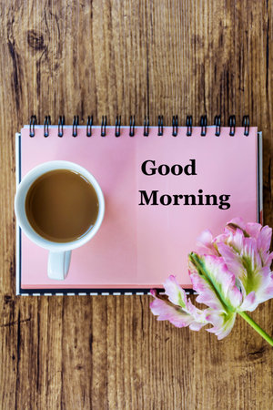 Good morning text on notepad and cup of coffee on wooden backgroundの写真素材