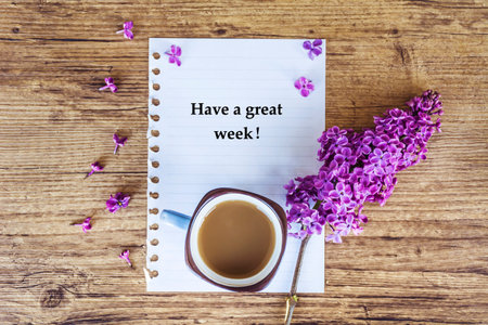 Cup of coffee, lilac flowers and notebook with textの写真素材