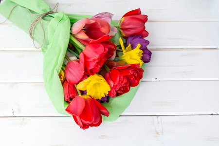 Bouquet of tulips and daffodils on white wooden backgroundの写真素材