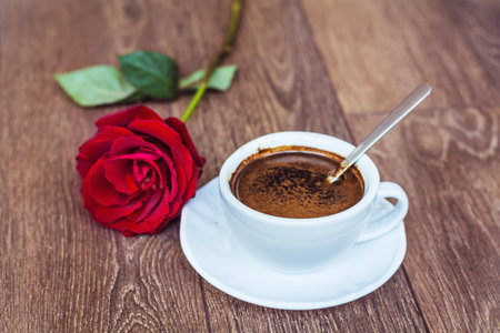 Coffee cup and red rose on wooden background. Valentines dayの写真素材