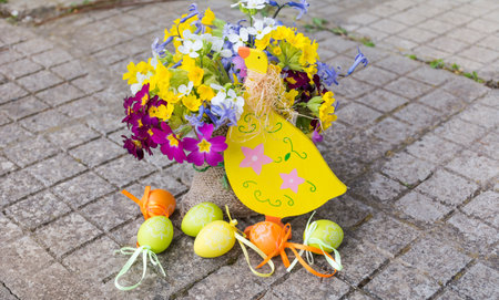 Easter basket with spring flowers and easter eggs on the pavementの写真素材