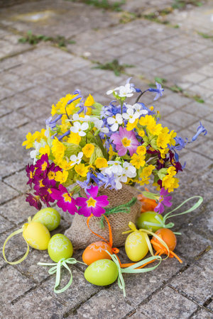 Bouquet of spring flowers and easter eggs in a basketの写真素材