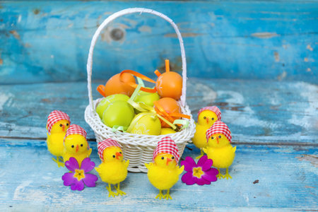 Easter eggs in a basket with chick on a blue wooden backgroundの写真素材