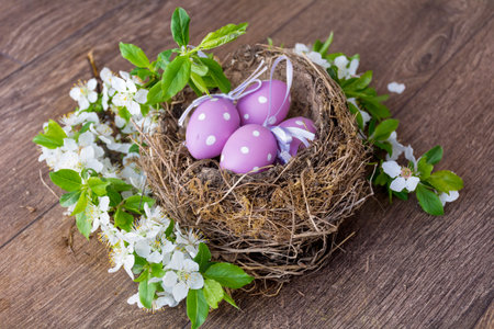 Easter eggs in a nest with spring flowers on a wooden backgroundの写真素材