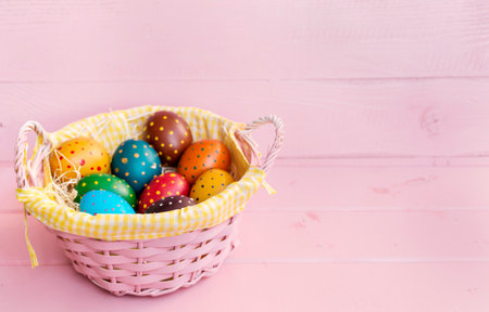 Colorful easter eggs in a basket on pink wooden background.の写真素材