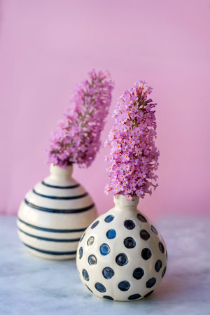 Bouquet of lilac flowers in vases on pink backgroundの写真素材