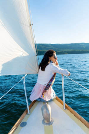 Young woman sitting on the deck of a sailboat and looking at the seaの写真素材