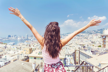 Back view of young woman with raised arms looking at the cityscape of Barcelona, Spainの写真素材