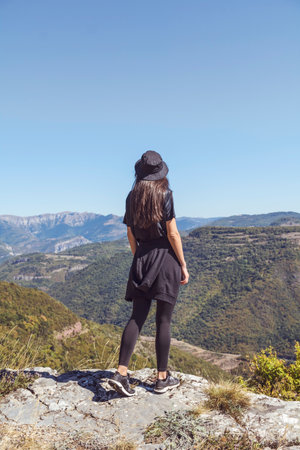 Young woman standing on top of a mountain and looking at the valleyの写真素材