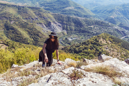 Young woman hiker on top of a mountain looking at the valleyの写真素材