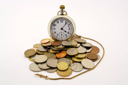 an antique pocket watch with gold fob surrounded by coins of the worldの写真素材