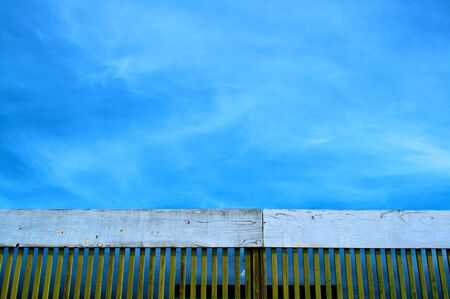Deep blue sky with lacy clounds above a old fenceの写真素材