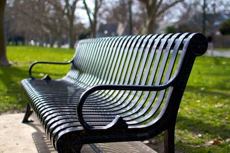 metal park bench tanken at an angle in city parkの写真素材