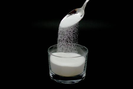 a spoonful of sugar falling into a glass cup taken at high speed to see granualesの写真素材