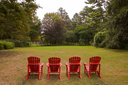 Four red adirondack chairs in a green meadow done in landscape vの写真素材