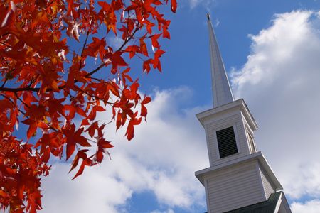 leaves that have turned red and church steeple against a blue skyの写真素材