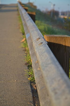 Steel gaurd rail along road with wood posts and soft focus green hilの写真素材