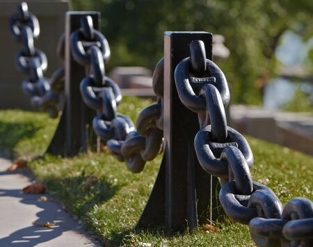 Black Steel Anchor Chain used for a railing againt grass lawnの写真素材