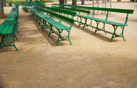 Rows of empty green park benches on gravel の写真素材