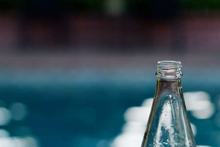 Top of empty glass bottle against a soft background of a poolの写真素材