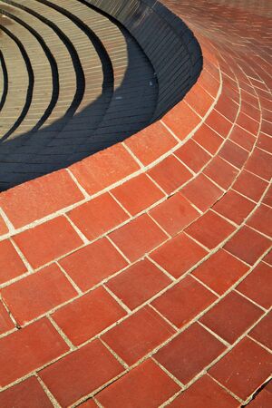 Red curved brick wall that comes to a ridge with steps on the other sideの写真素材