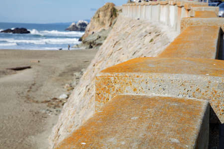 Thick concrete wall along pedestrian walk and street near ocean coastの写真素材