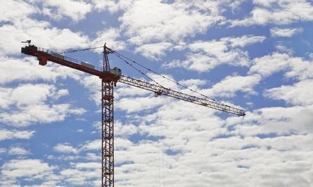Red city crane against blue sky with puffy white cloudsの写真素材