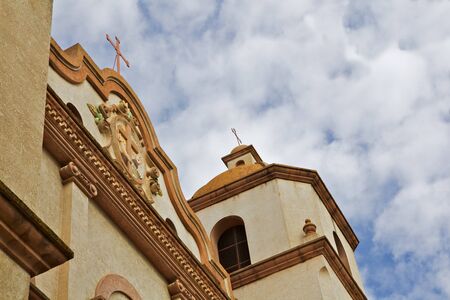 Abstract shot of old mission style church with puffy clouds and blue sky in backgroundの写真素材