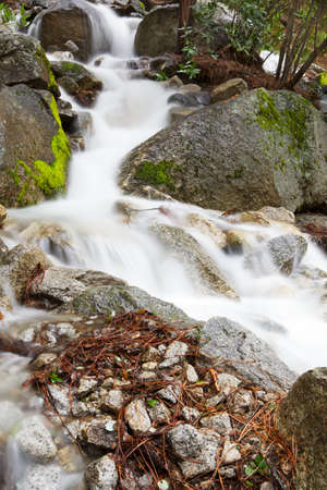 Frothy mountain stream through moss covered boulders capture with a long exposure
